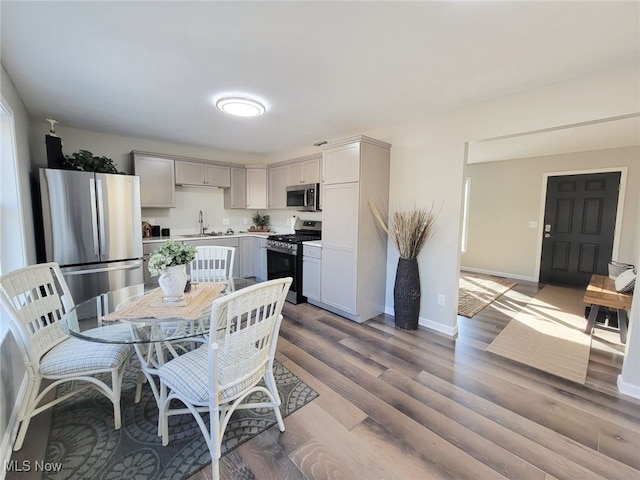 interior space with gray cabinets, sink, light wood-type flooring, and stainless steel appliances