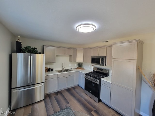 kitchen featuring gray cabinetry, sink, stainless steel appliances, and dark wood-type flooring