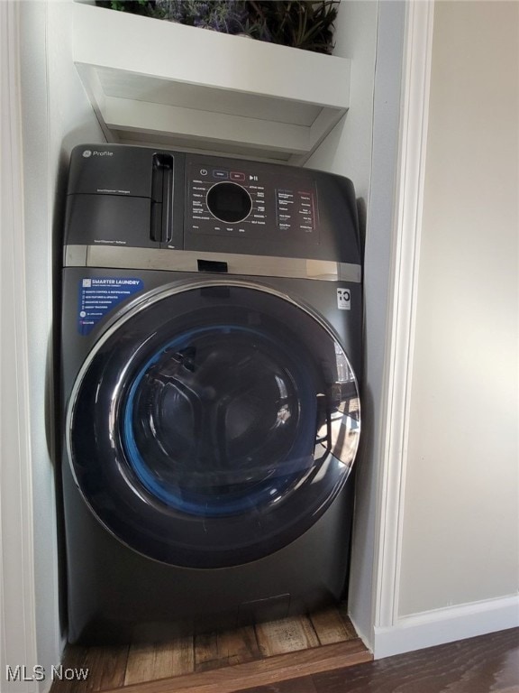 clothes washing area featuring washer / clothes dryer and dark hardwood / wood-style flooring