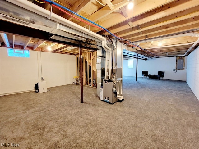 basement featuring electric panel, heating unit, and carpet floors