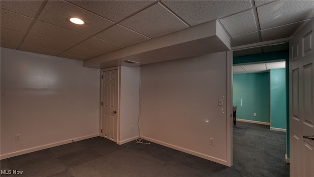 basement featuring a drop ceiling and dark colored carpet