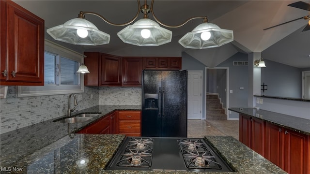 kitchen with black appliances, decorative light fixtures, sink, and dark stone countertops