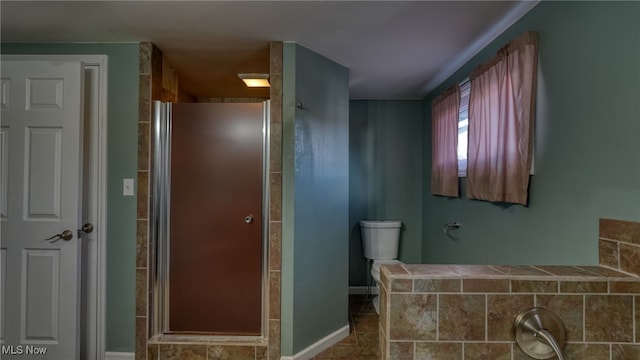 bathroom featuring a shower with door and toilet