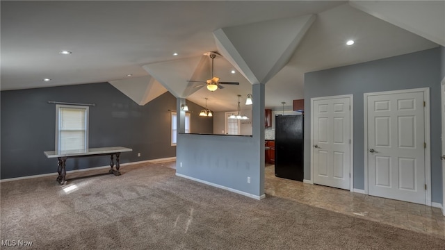 kitchen featuring ceiling fan with notable chandelier, black fridge, carpet floors, and vaulted ceiling