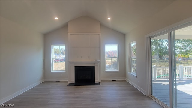 unfurnished living room featuring a large fireplace, light hardwood / wood-style floors, and vaulted ceiling