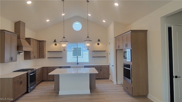 kitchen with a wealth of natural light, a kitchen island, appliances with stainless steel finishes, and wall chimney exhaust hood