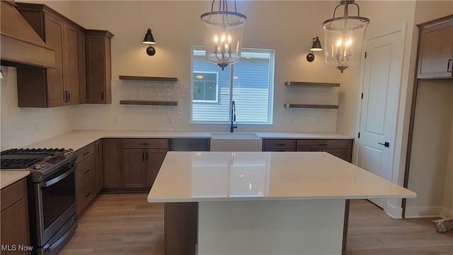 kitchen with pendant lighting, light hardwood / wood-style floors, an inviting chandelier, and gas range