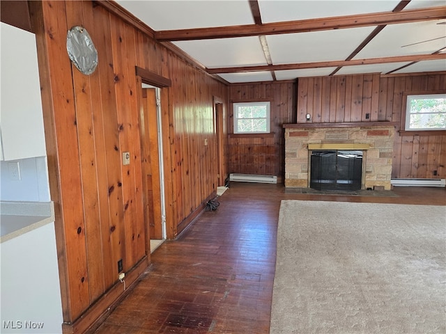 unfurnished living room featuring dark wood-type flooring, a wealth of natural light, baseboard heating, and wood walls