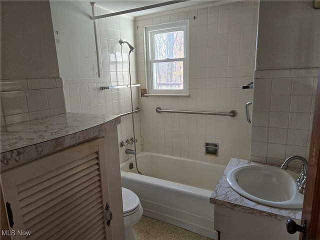 full bathroom featuring toilet, vanity, tiled shower / bath, and tile walls