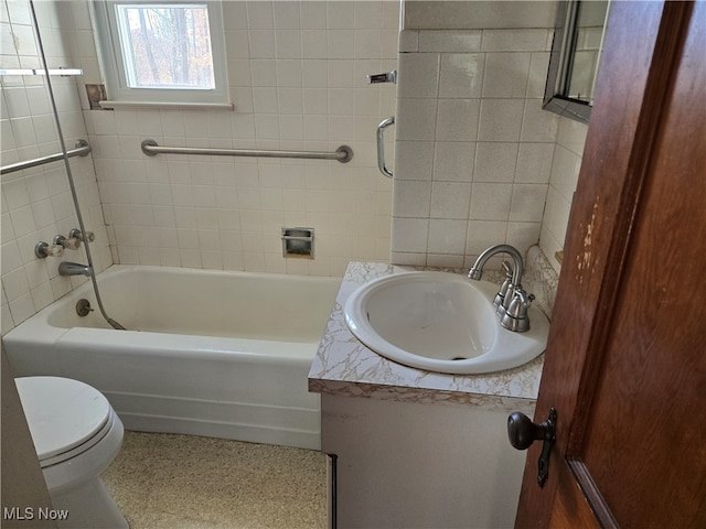 full bathroom featuring toilet, vanity, tiled shower / bath, and tile walls