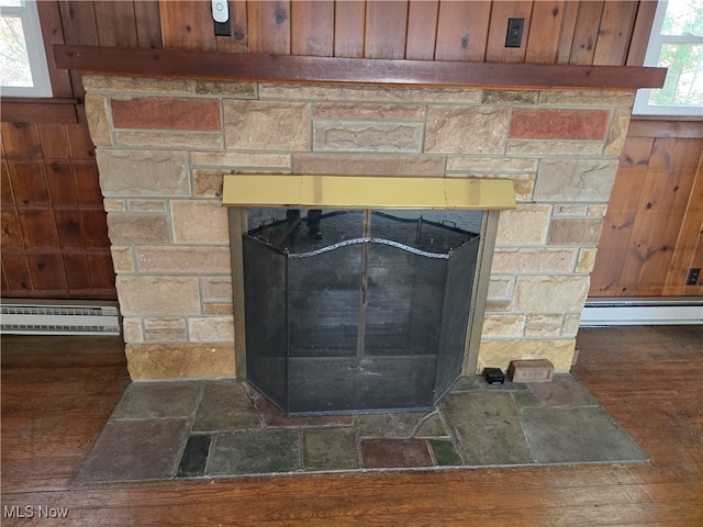 details with a stone fireplace, a baseboard heating unit, and hardwood / wood-style flooring