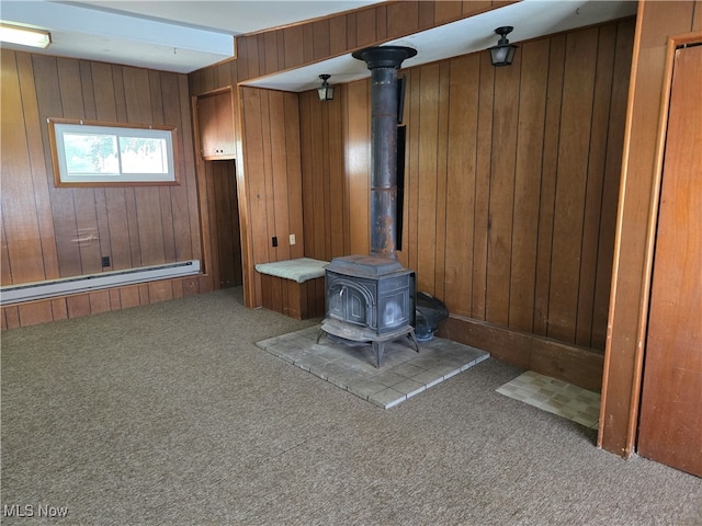 interior space with a wood stove, baseboard heating, and wood walls