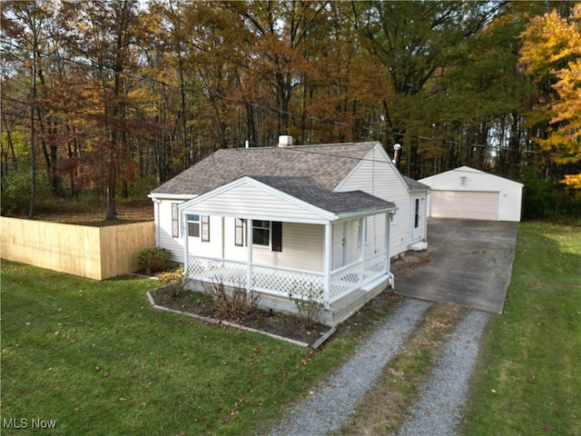 view of front facade featuring covered porch, a garage, a front lawn, and an outbuilding