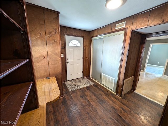 foyer entrance featuring wood-type flooring and wooden walls