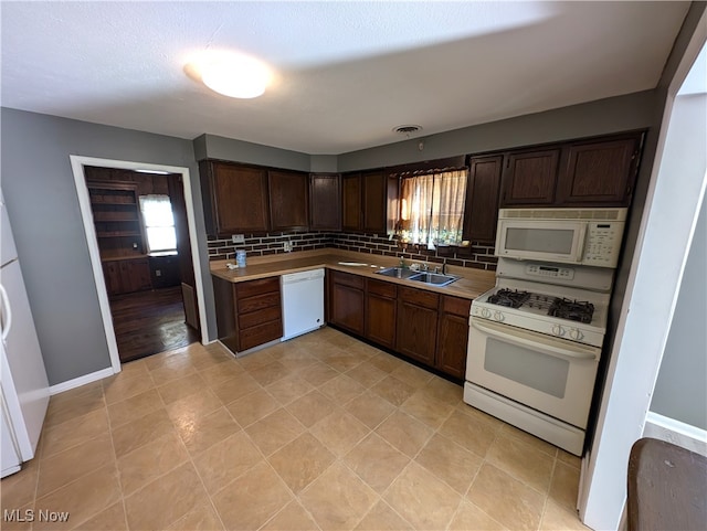 kitchen with dark brown cabinets, tasteful backsplash, white appliances, and sink