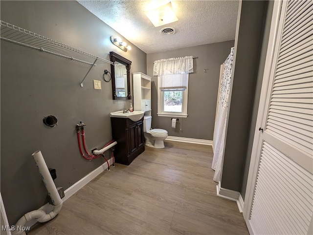 bathroom with toilet, vanity, wood-type flooring, and a textured ceiling