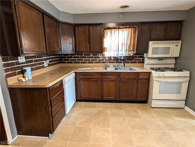 kitchen with light tile patterned flooring, sink, backsplash, white appliances, and dark brown cabinets