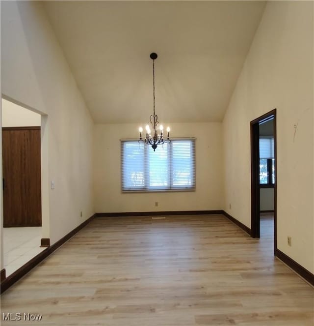 unfurnished dining area with high vaulted ceiling, light wood-type flooring, and an inviting chandelier