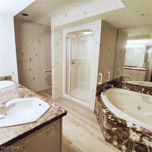 bathroom with vanity, separate shower and tub, hardwood / wood-style floors, and a textured ceiling