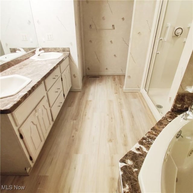 bathroom with hardwood / wood-style flooring, vanity, and plus walk in shower