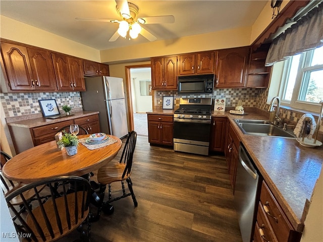 kitchen with stainless steel appliances, sink, tasteful backsplash, ceiling fan, and dark wood-type flooring