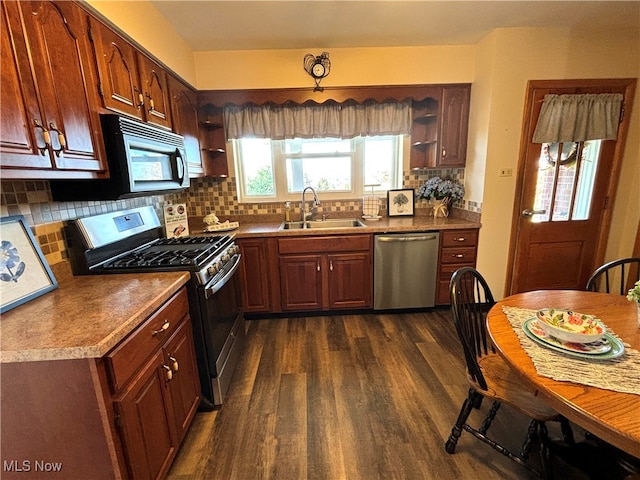 kitchen with stainless steel appliances, sink, decorative light fixtures, backsplash, and dark hardwood / wood-style flooring