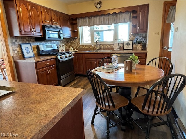 kitchen featuring dark hardwood / wood-style flooring, sink, decorative backsplash, and appliances with stainless steel finishes