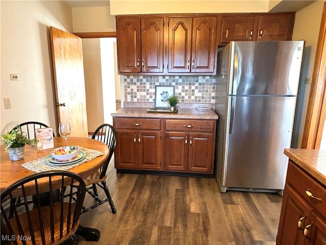 kitchen with decorative backsplash, dark hardwood / wood-style flooring, and stainless steel fridge