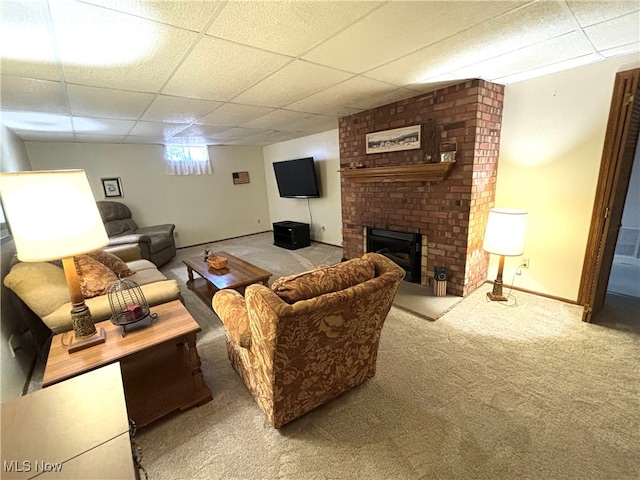 living room featuring a drop ceiling, a brick fireplace, and light carpet