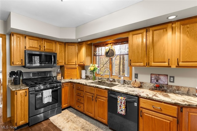 kitchen with appliances with stainless steel finishes, dark wood-type flooring, sink, and light stone counters