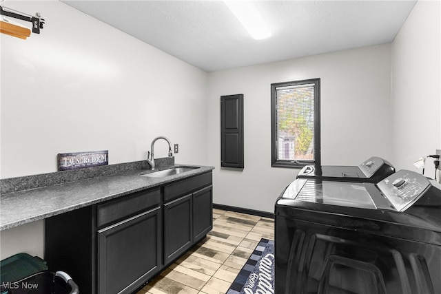 clothes washing area featuring cabinets, light hardwood / wood-style flooring, sink, and washing machine and clothes dryer