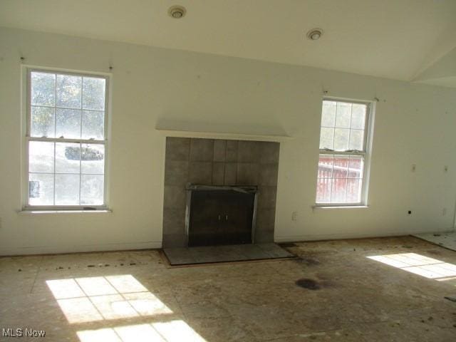 unfurnished living room featuring a fireplace and a healthy amount of sunlight