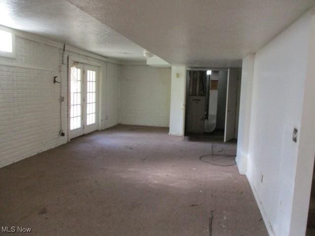 basement featuring brick wall and a textured ceiling