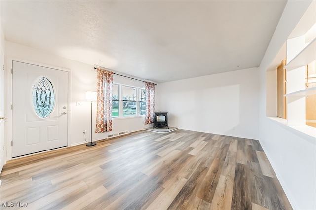 foyer entrance featuring a wood stove and light hardwood / wood-style flooring