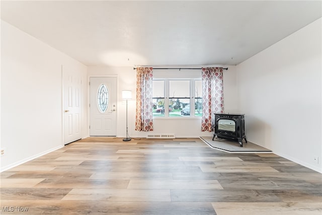 entrance foyer with a wood stove and light hardwood / wood-style flooring