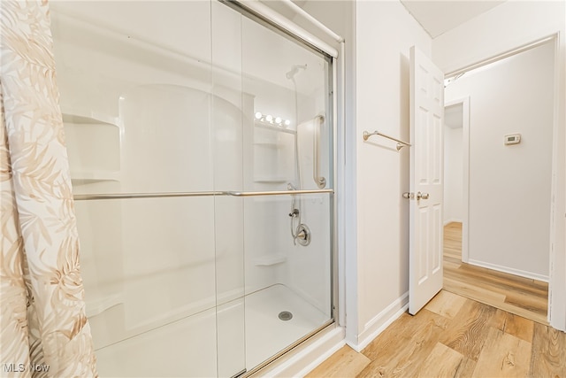 bathroom with hardwood / wood-style floors and a shower with door