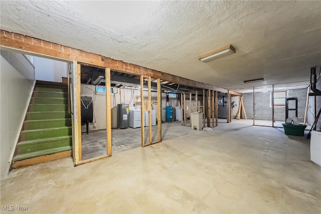 basement with electric water heater, a textured ceiling, and washer / dryer