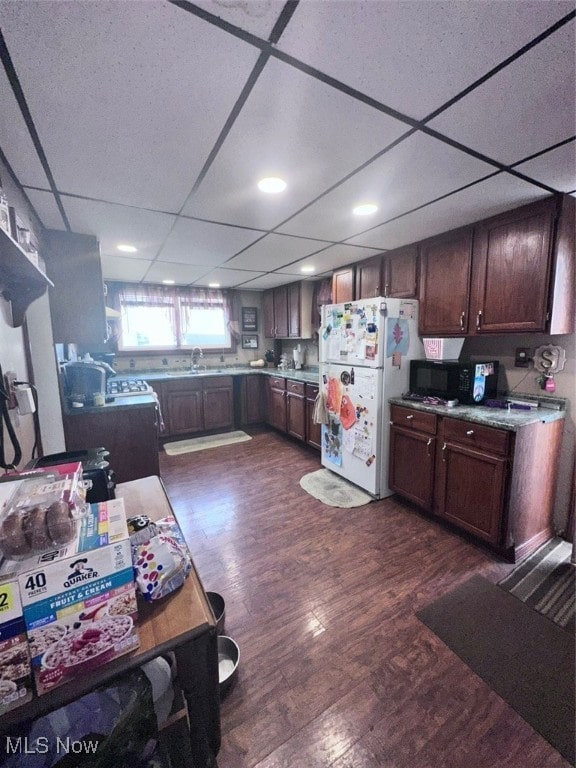 kitchen featuring dark wood-type flooring, a paneled ceiling, sink, and white refrigerator