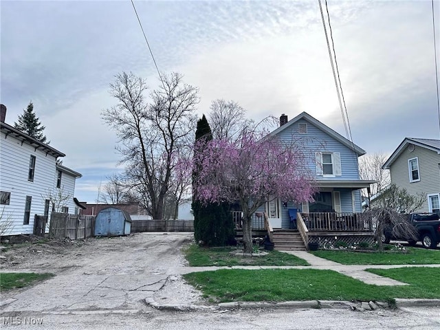 47 Swan St, Geneva, OH 44041 - view of front of home featuring a storage unit, a porch, a chimney, fence, and an outdoor structure