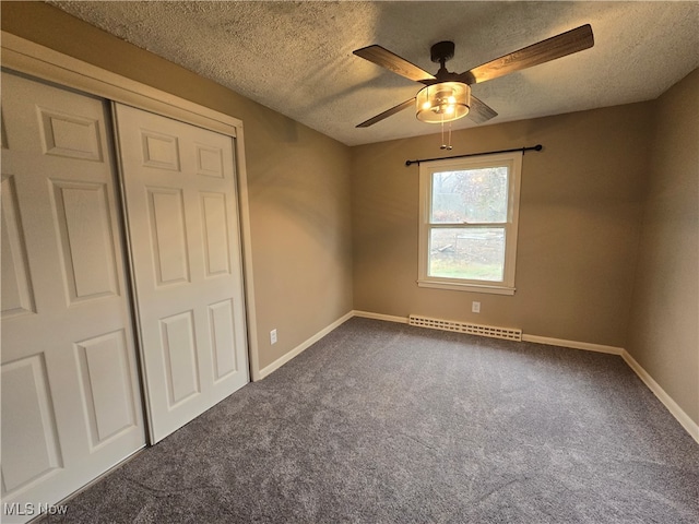 unfurnished bedroom with ceiling fan, a baseboard heating unit, carpet floors, and a textured ceiling