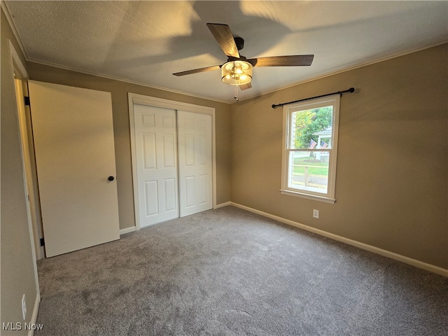 unfurnished bedroom featuring carpet, a closet, ceiling fan, and ornamental molding