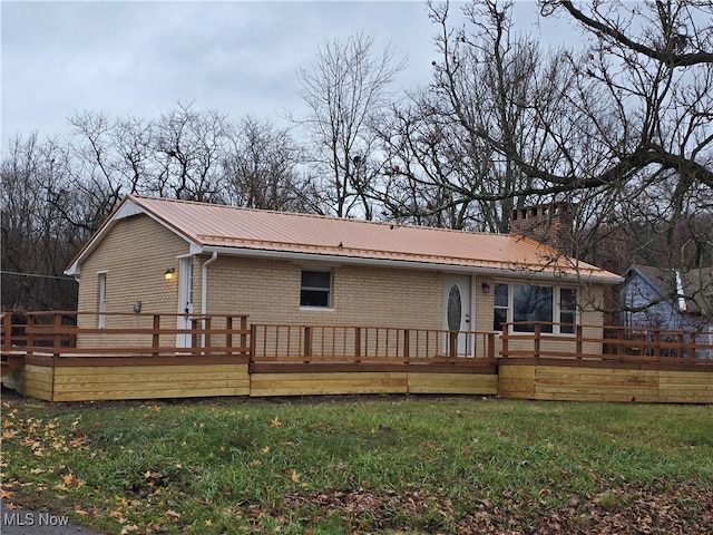 back of property featuring a deck and a lawn