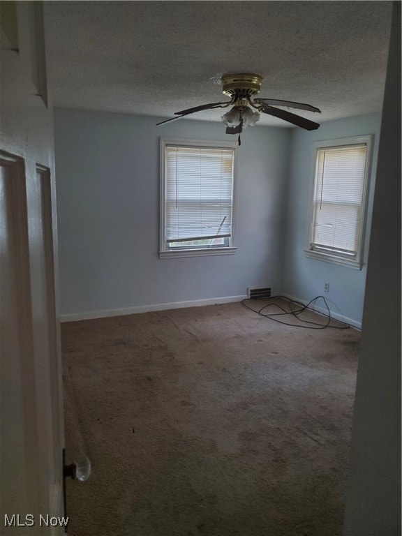 carpeted spare room featuring a textured ceiling and ceiling fan