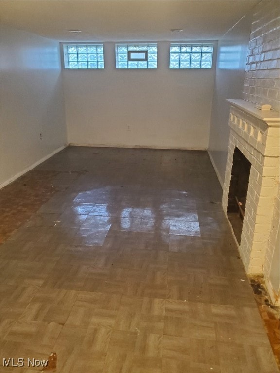 basement featuring plenty of natural light and a brick fireplace