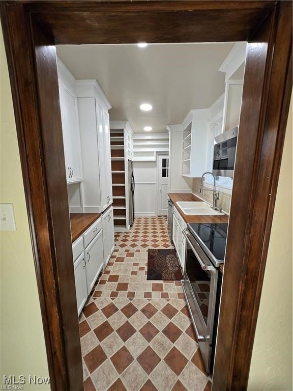 kitchen with stainless steel appliances, white cabinetry, and sink