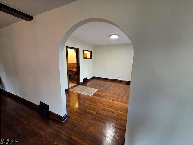 spare room with beamed ceiling and dark hardwood / wood-style floors