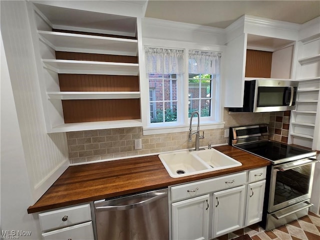 kitchen featuring stainless steel appliances, white cabinetry, sink, tasteful backsplash, and wooden counters