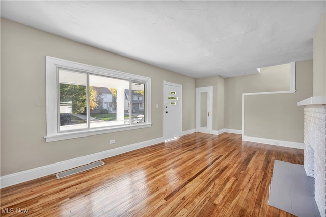 unfurnished living room featuring a fireplace and light hardwood / wood-style flooring