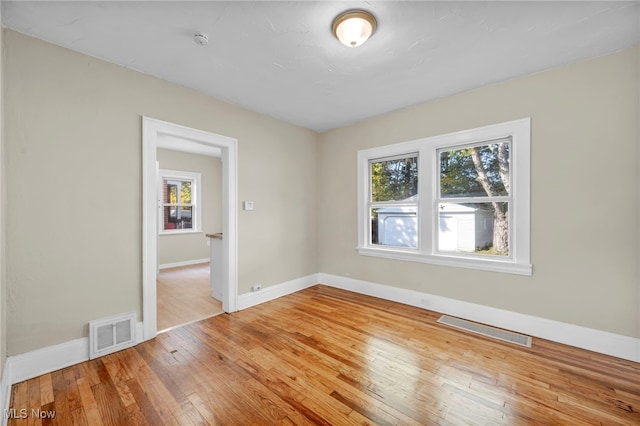 empty room with a wealth of natural light and wood-type flooring