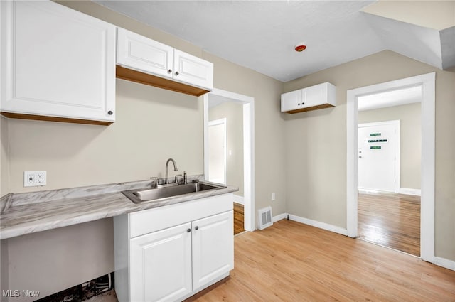 kitchen with white cabinets, sink, and light hardwood / wood-style flooring